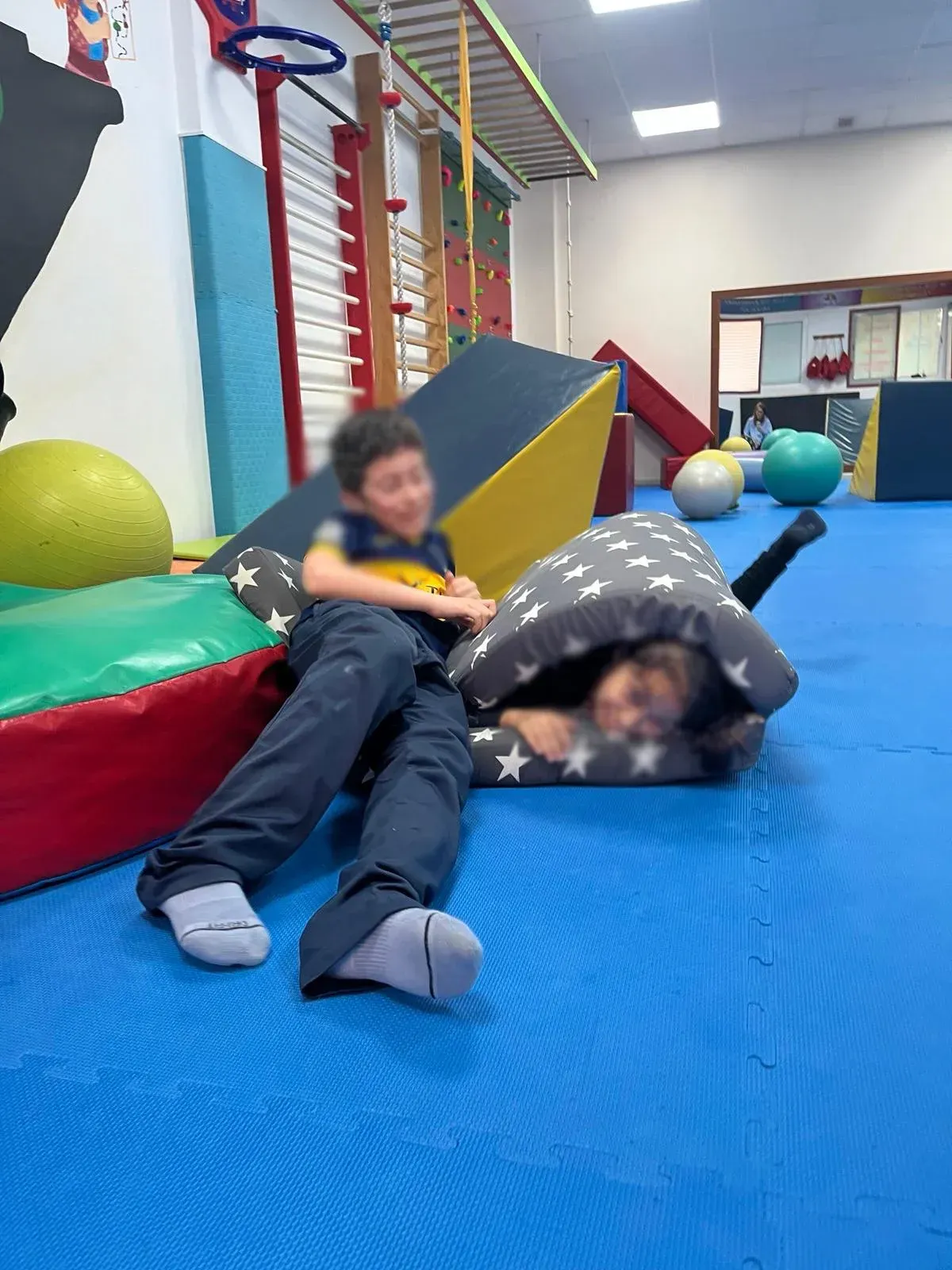 Dos niños están acostados en el suelo en un gimnasio.