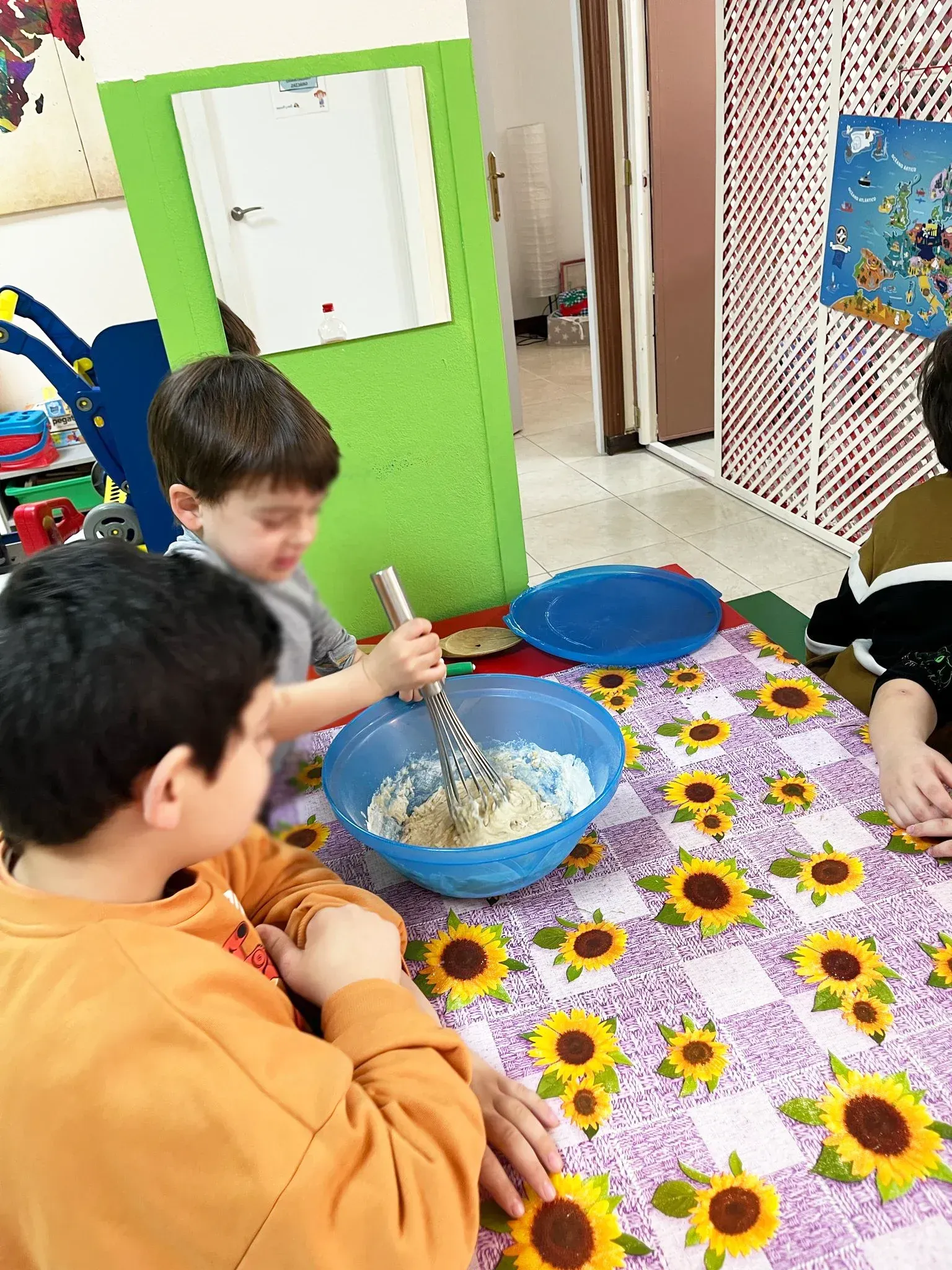 Un grupo de niños está sentado en una mesa mezclando ingredientes en un tazón.