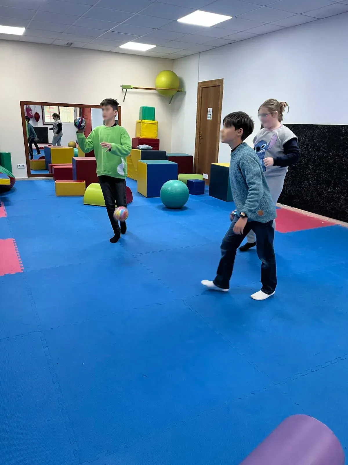 Un grupo de niños está jugando con pelotas en un gimnasio.