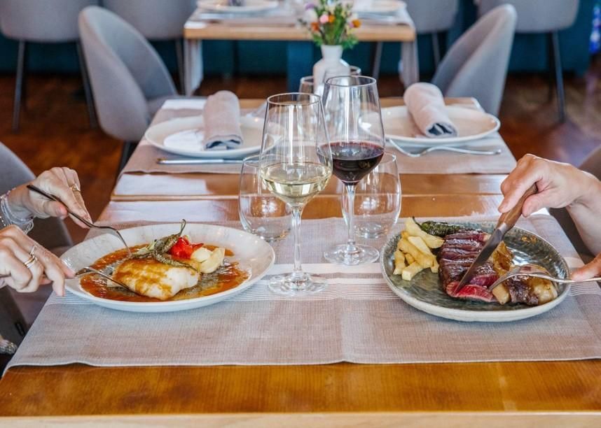 Mujer colocando una servilleta enrollada en un plato en una mesa preparada para cenar.