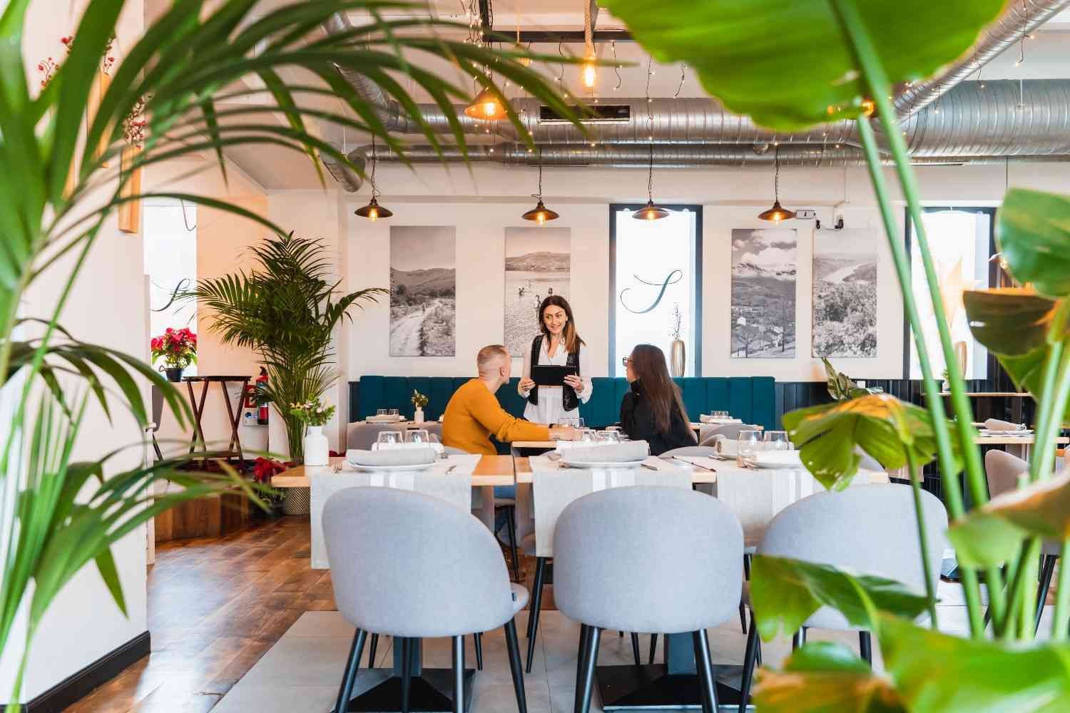 Interior de restaurante con clientes en una mesa atendidos por un camarero