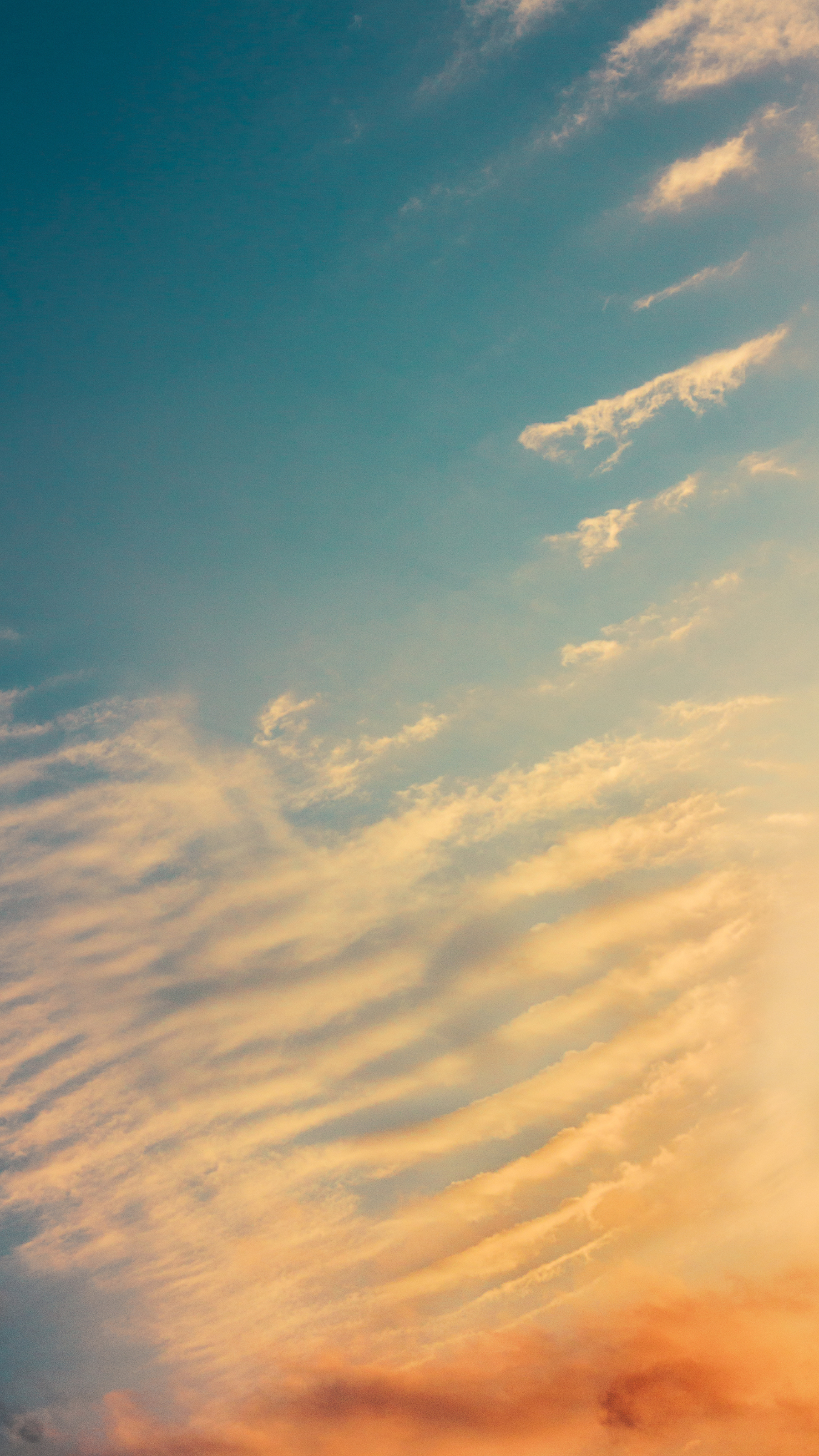 Ciel bleu et orange avec de fins nuages.