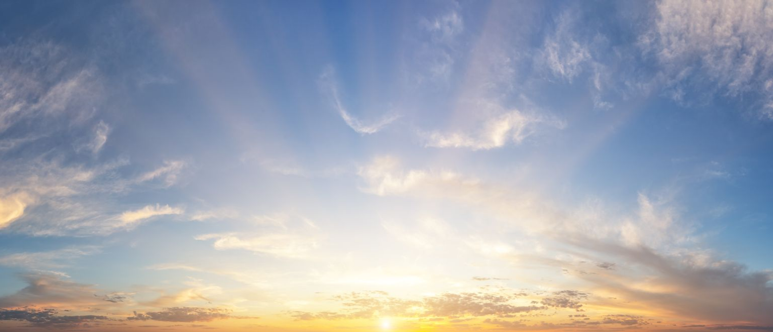Ciel bleu parsemé de nuages ​​vaporeux et lever de soleil doré.