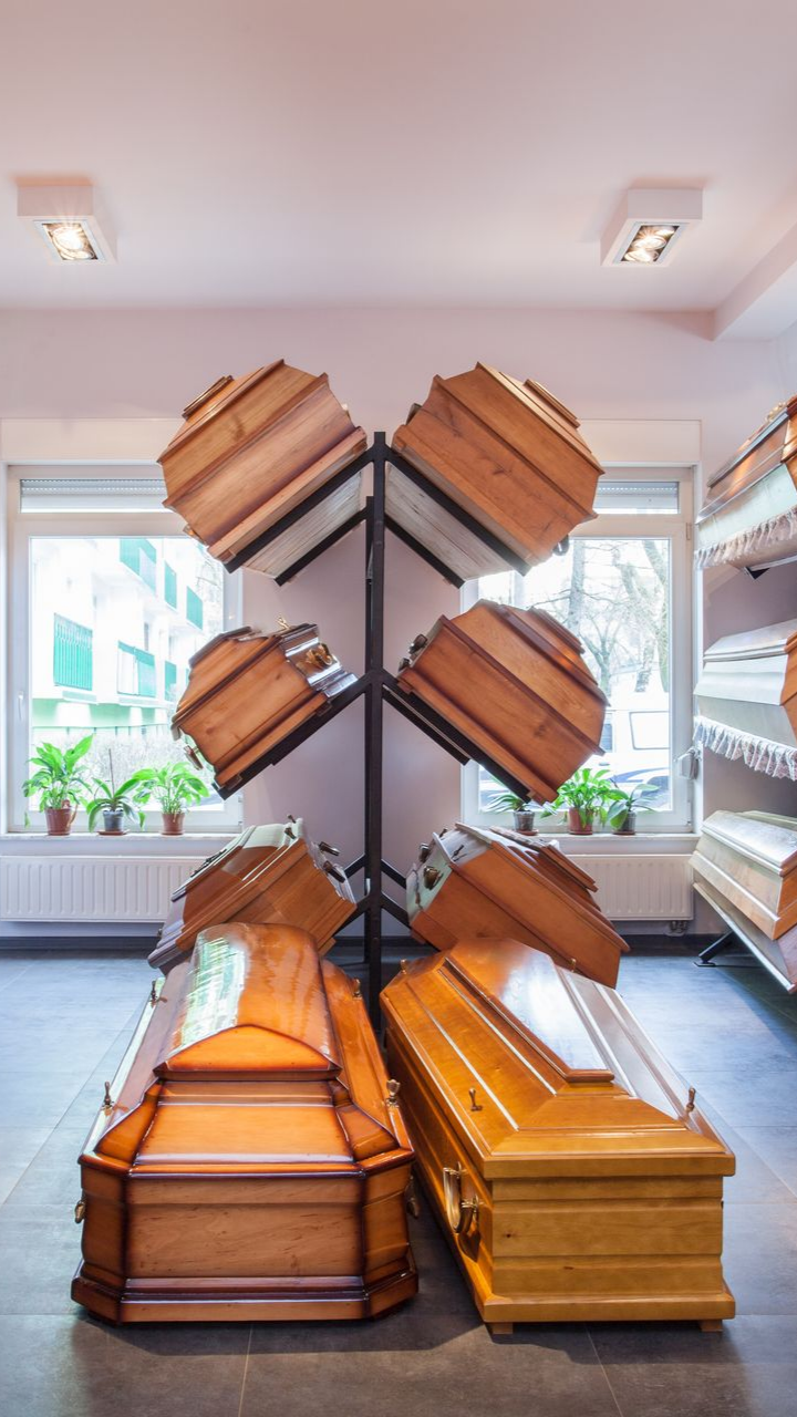 Salle d'exposition d'une entreprise de pompes funèbres présentant divers cercueils en bois.