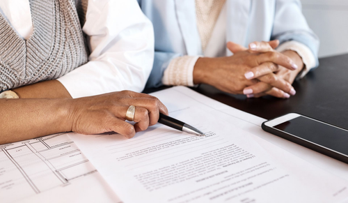 Deux personnes assises à une table examinent des documents administratifs.