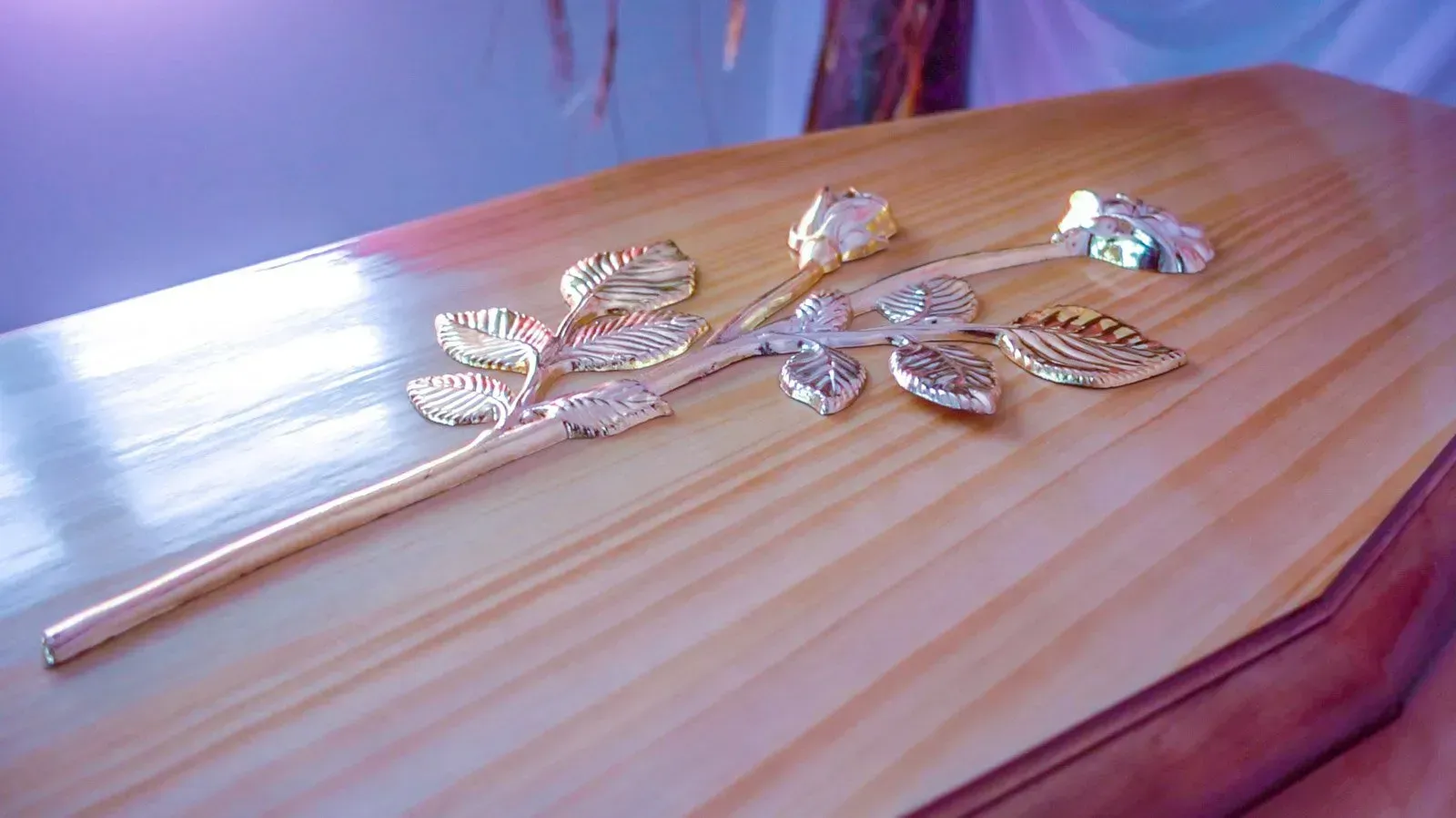 Cercueil en bois orné d'une rose décorative en métal.