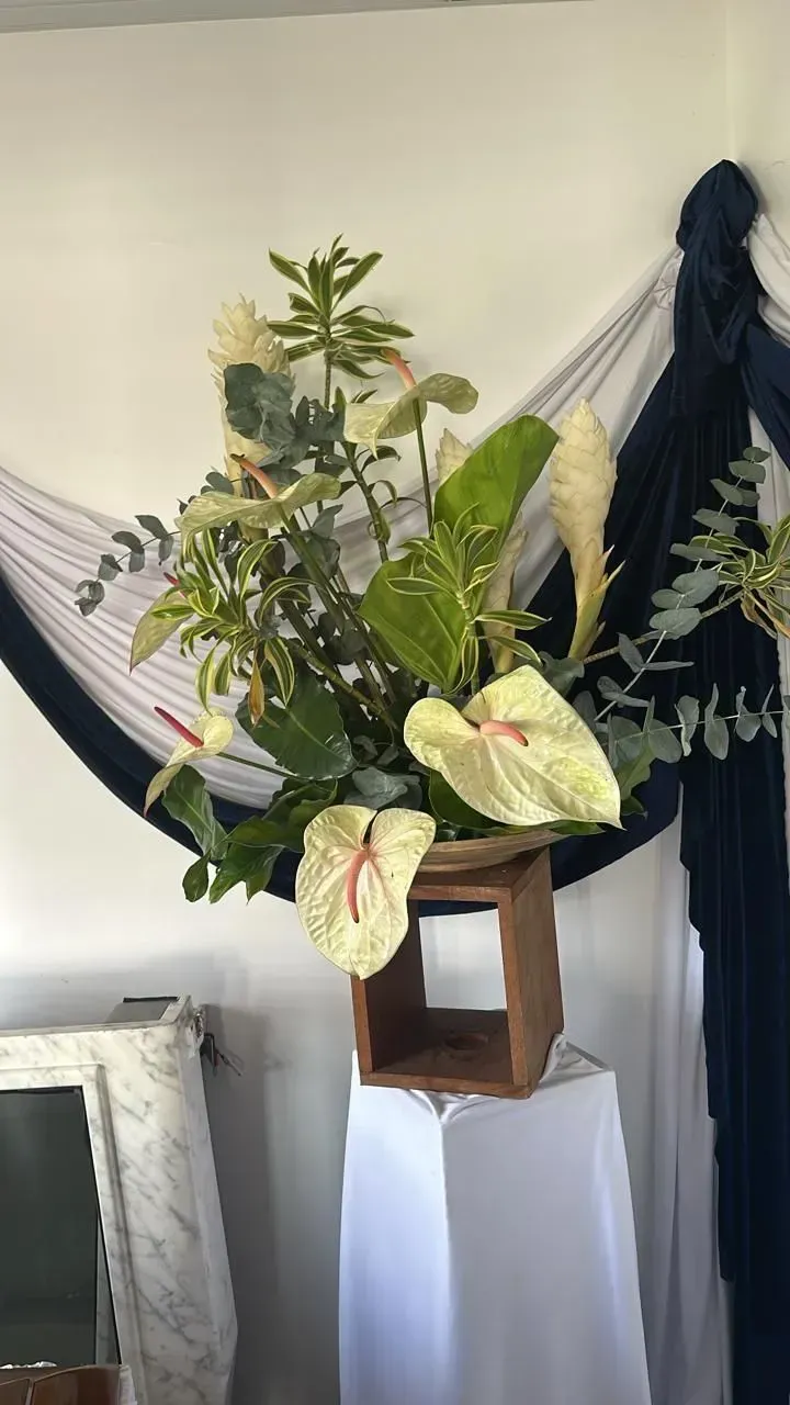 Composition florale sur une table recouverte d'un drap blanc, avec un fond en tissu blanc et bleu marine.