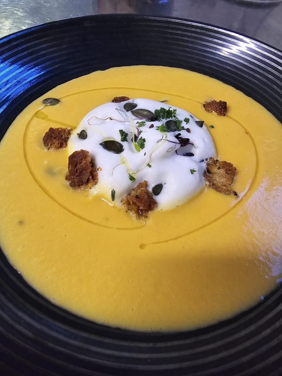 Un bol de soupe avec de la crème fouettée et des croûtons dessus