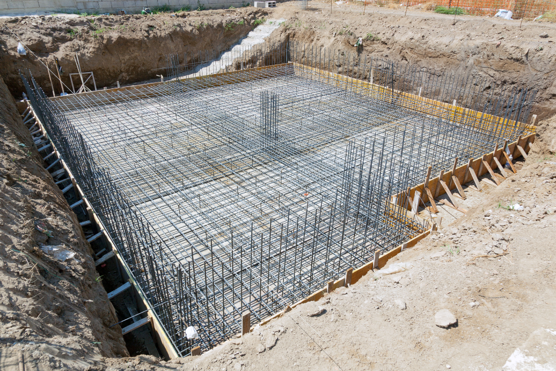 Une fondation en béton est en train d'être construite dans un trou dans le sol.