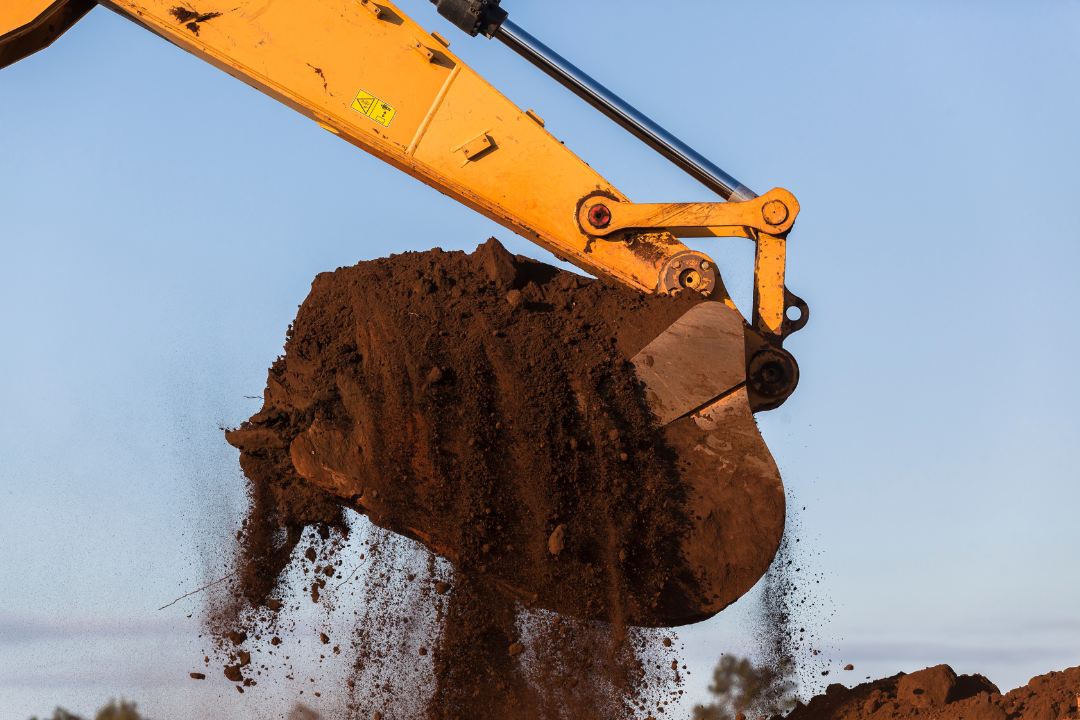 Un bulldozer jaune est assis sur un tas de terre.