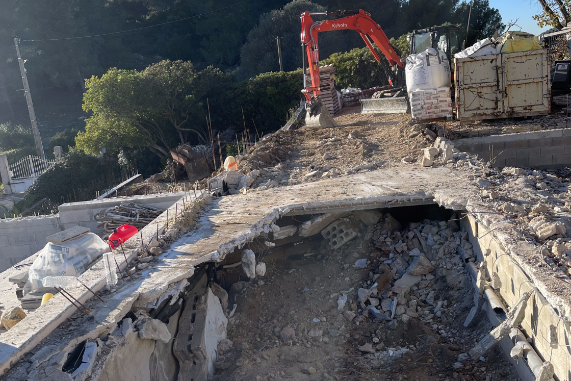 Un chantier avec une grande excavatrice et une benne à ordures.