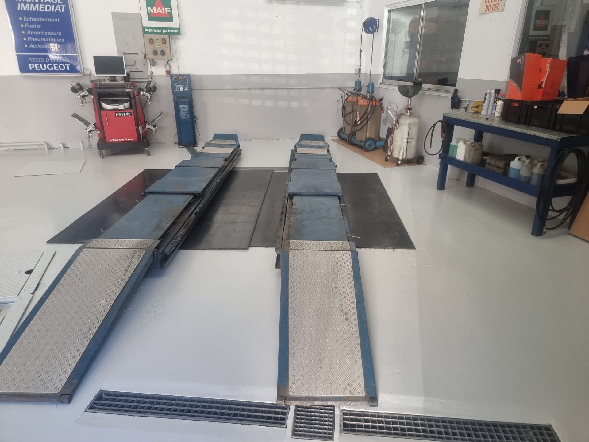 Monte-voiture dans un garage, rampes, bleu et gris métallisé, cadre professionnel.