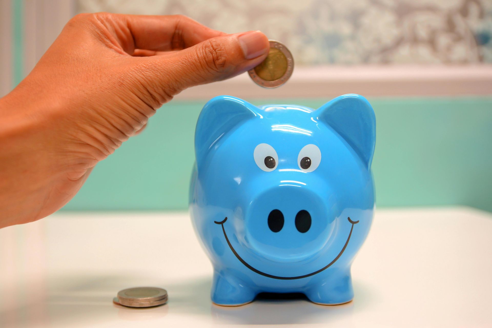 Una persona está poniendo una moneda en una alcancía azul.