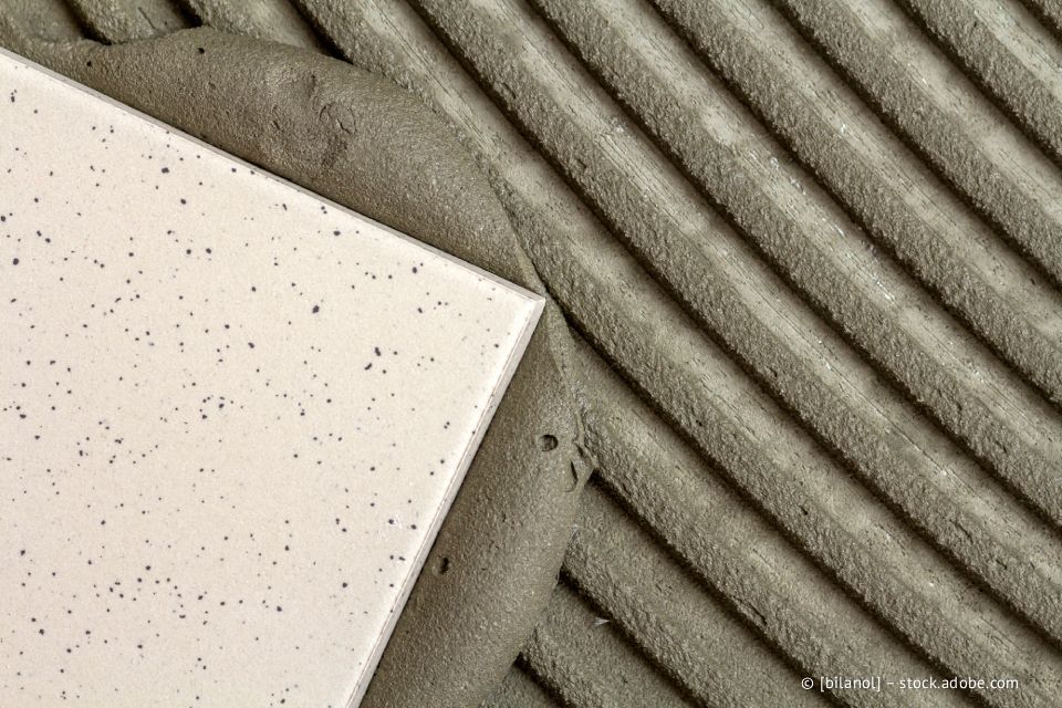 Fliesen werden auf frischem Mörtel verlegt, wodurch die Struktur und die Rillen sichtbar werden.