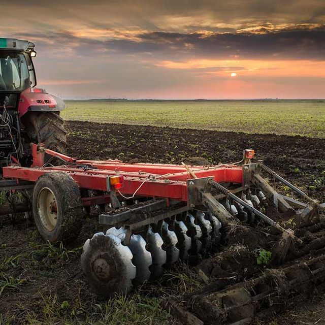 Un tractor está arando un campo con un arado de disco acoplado a él.