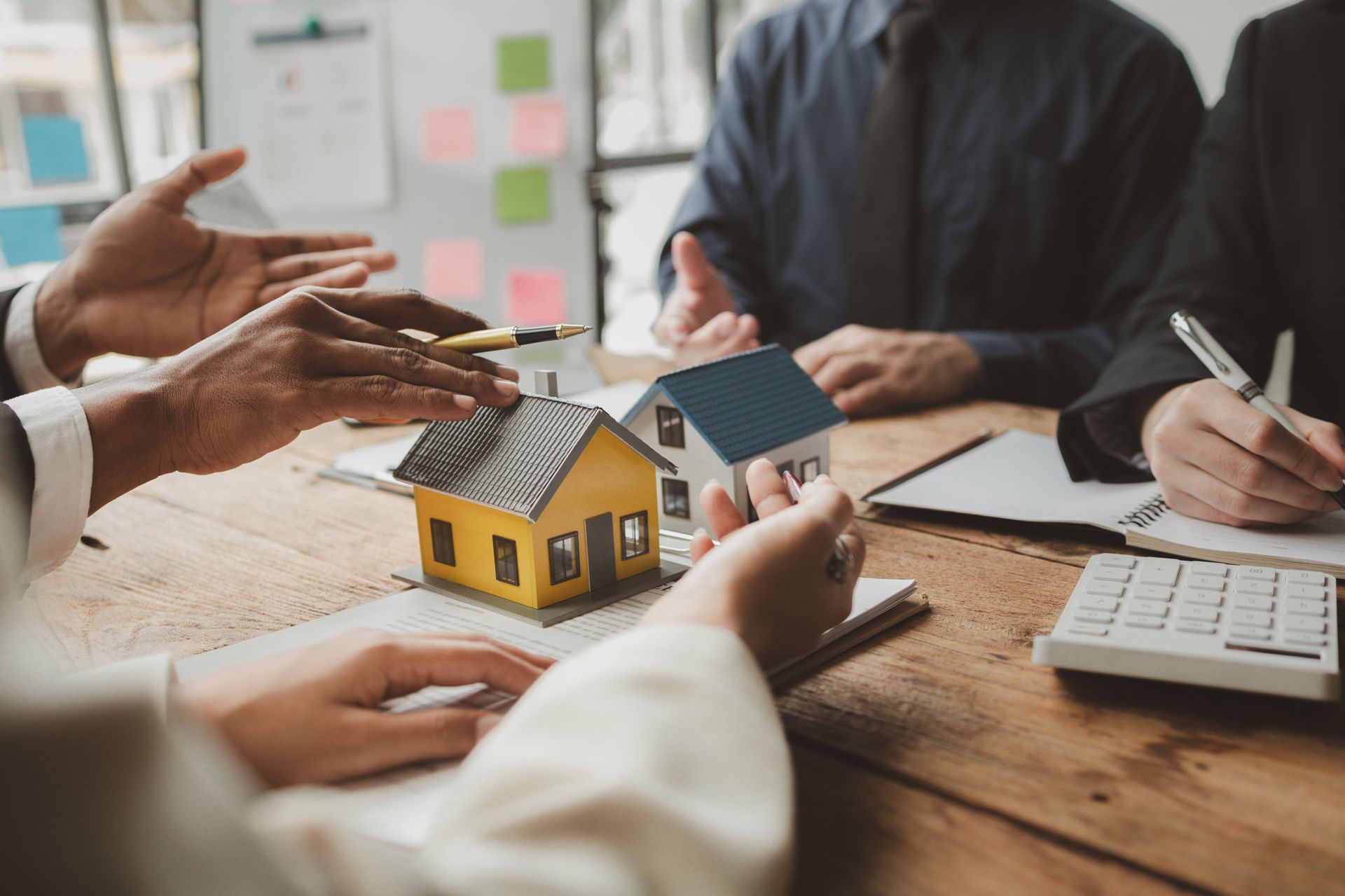 Un grupo de personas está sentada alrededor de una mesa mirando una casa modelo.