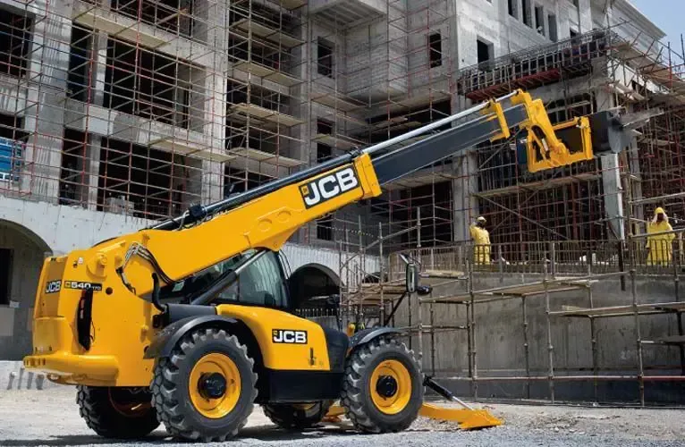 Una carretilla elevadora JCB amarilla está estacionada frente a un edificio en construcción.