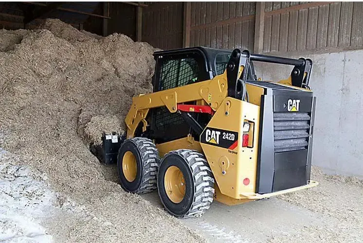 Una minicargadora de color amarillo y negro se encuentra en un almacén.