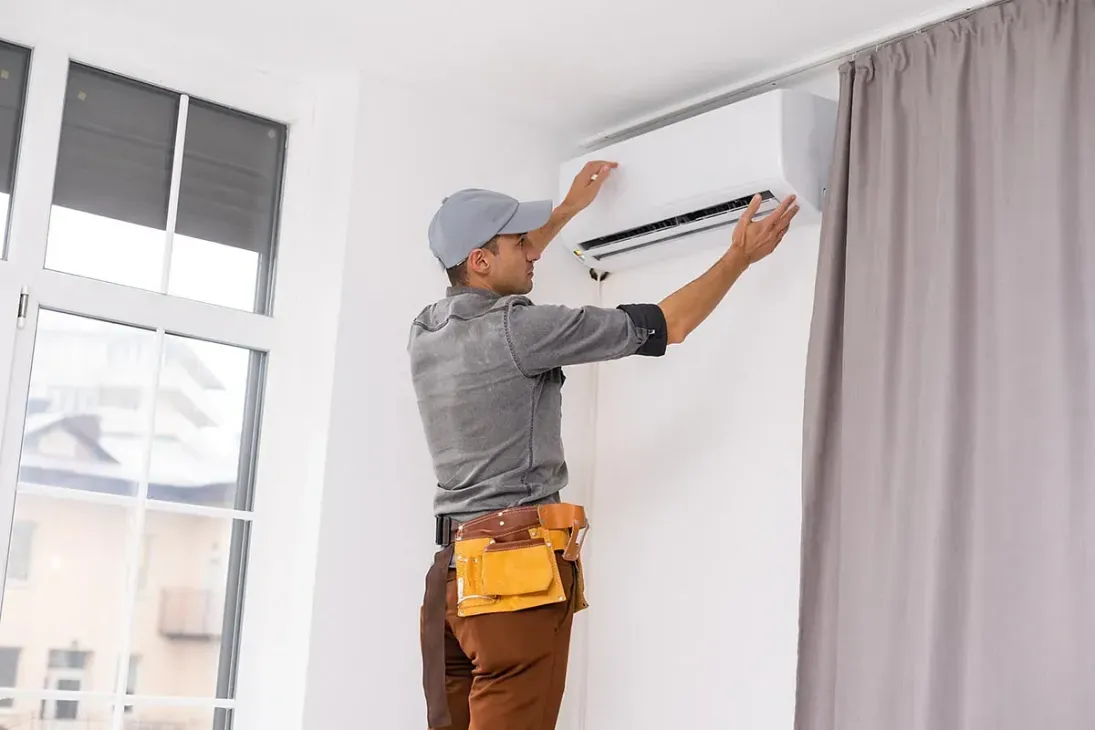 Un hombre está instalando un aire acondicionado en una sala de estar.