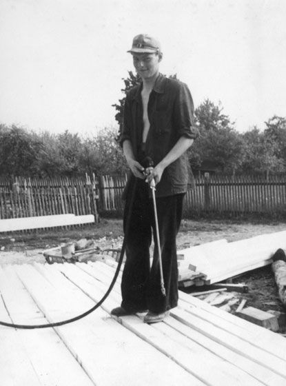 Schwarz-Weiß-Bild, ein Mann flammt Holz ab