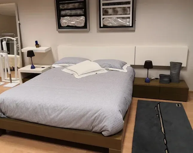 Un dormitorio minimalista con una cama con ropa de cama gris estampada