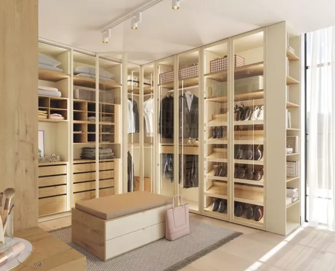 Un vestidor amplio y moderno con estantes de madera, perchero, organizadores blancos y un sillón blanco.