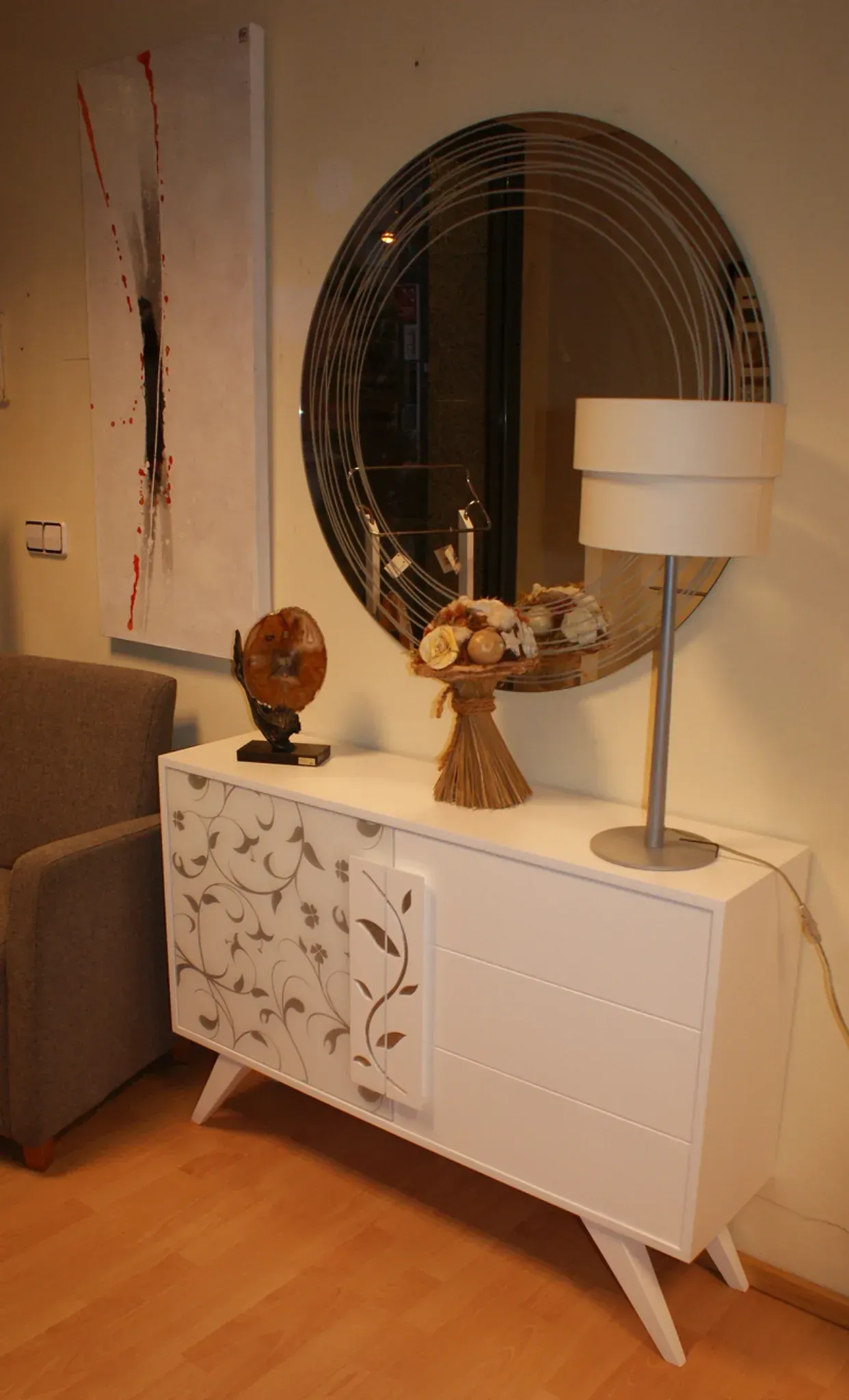 Un aparador blanco con una puerta estampada se encuentra debajo