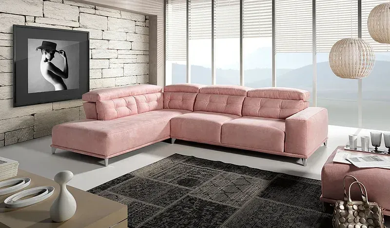 Un sofá seccional rosa en forma de L en una habitación moderna con una pared decorativa de piedra, una alfombra