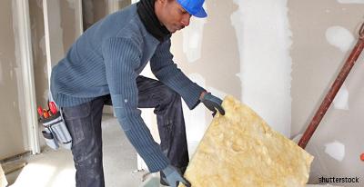 Un ouvrier manipule une plaque de laine de verre sur un chantier