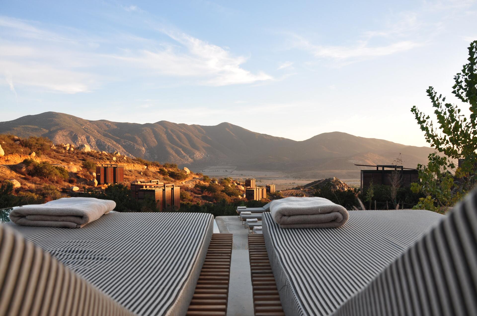 Two striped lounge chairs with towels on them with mountains in the background