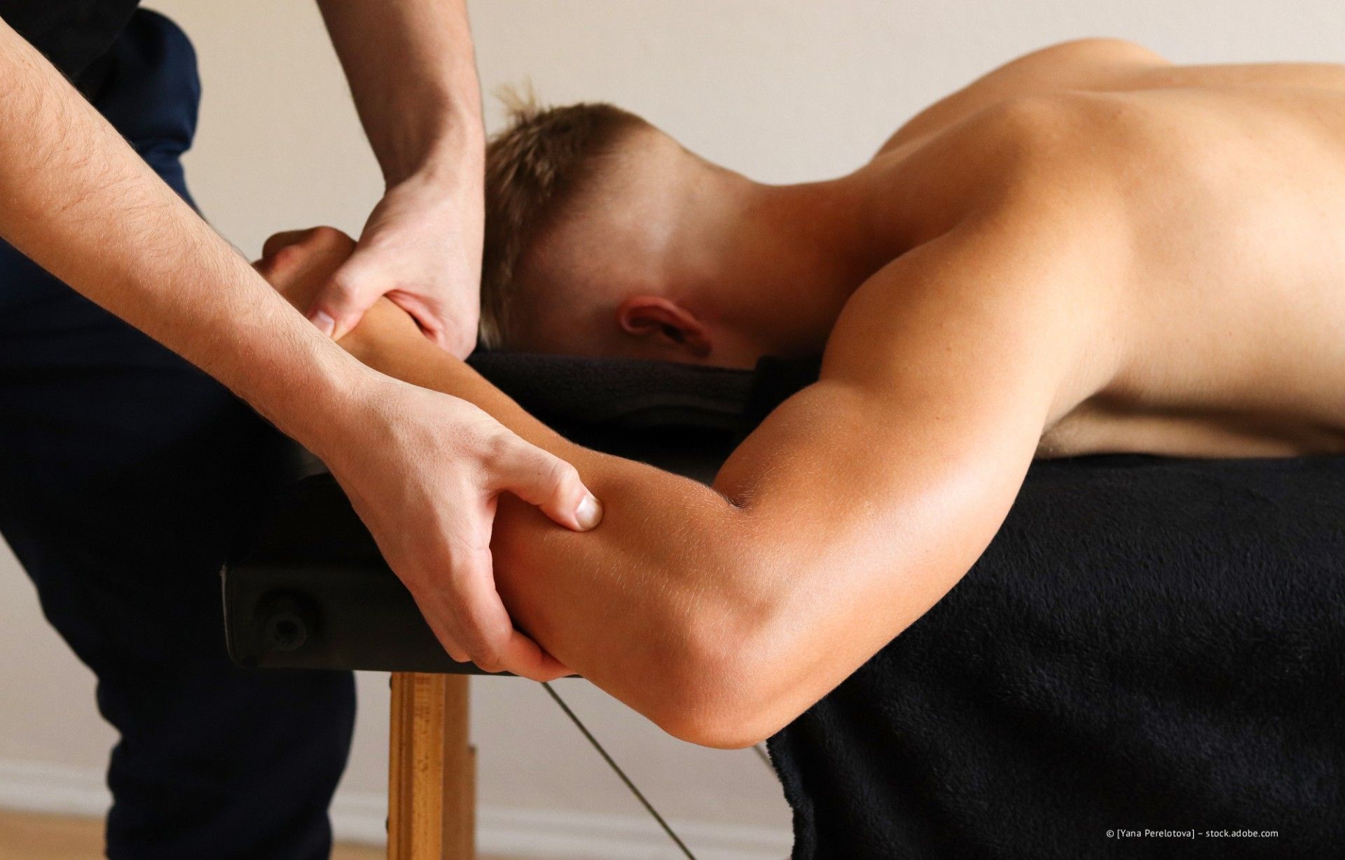 Hände massieren den bedeckten Bauch einer Person in einem hell erleuchteten Raum.