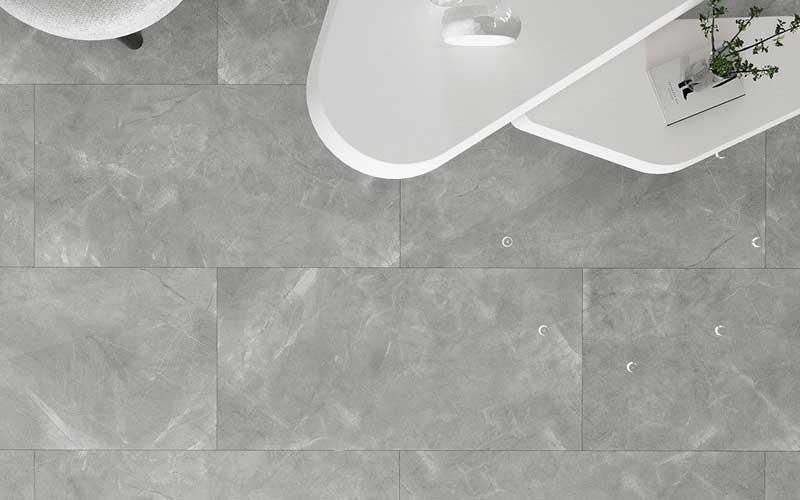 Ein grauer Fliesenboden mit einem weißen Tisch im Hintergrund.