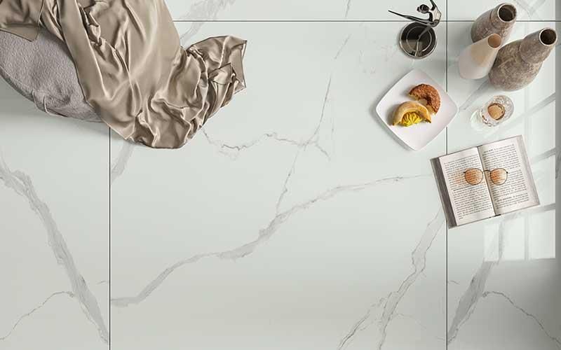 Ein weißer Fliesenboden mit einem Teller Essen und einem Buch darauf.