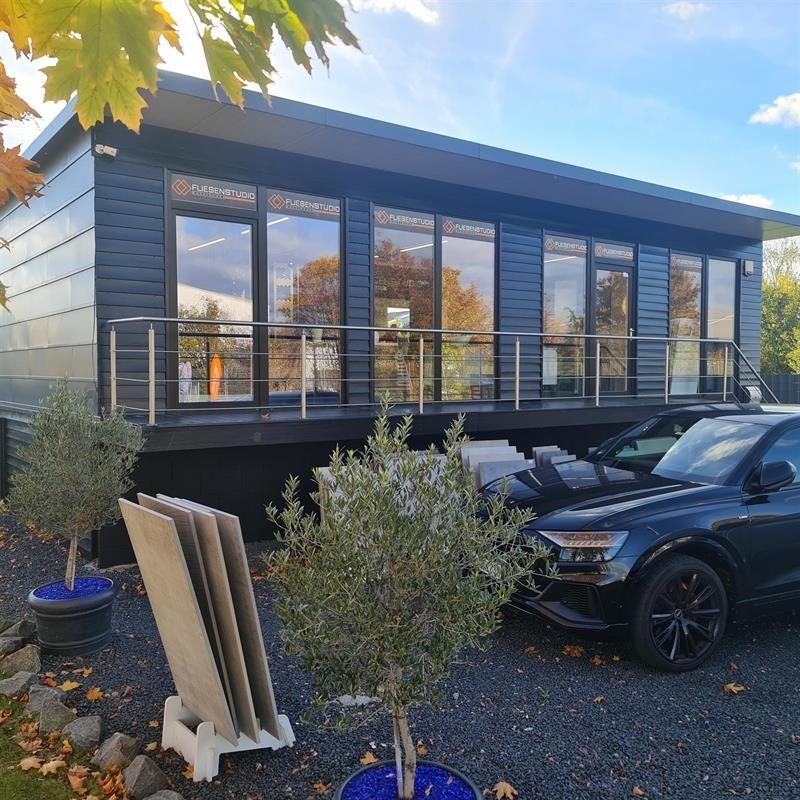Ein schwarzes Auto steht vor einem Gebäude mit vielen Fenstern