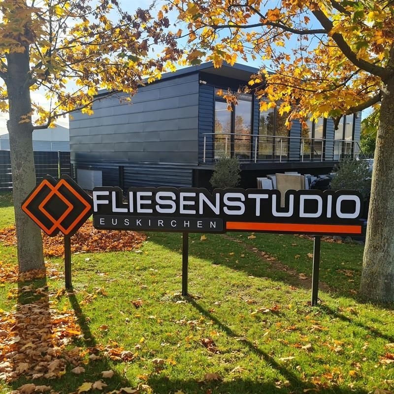 Ein Schild mit der Aufschrift „Fliesenstudio“ vor einem Haus