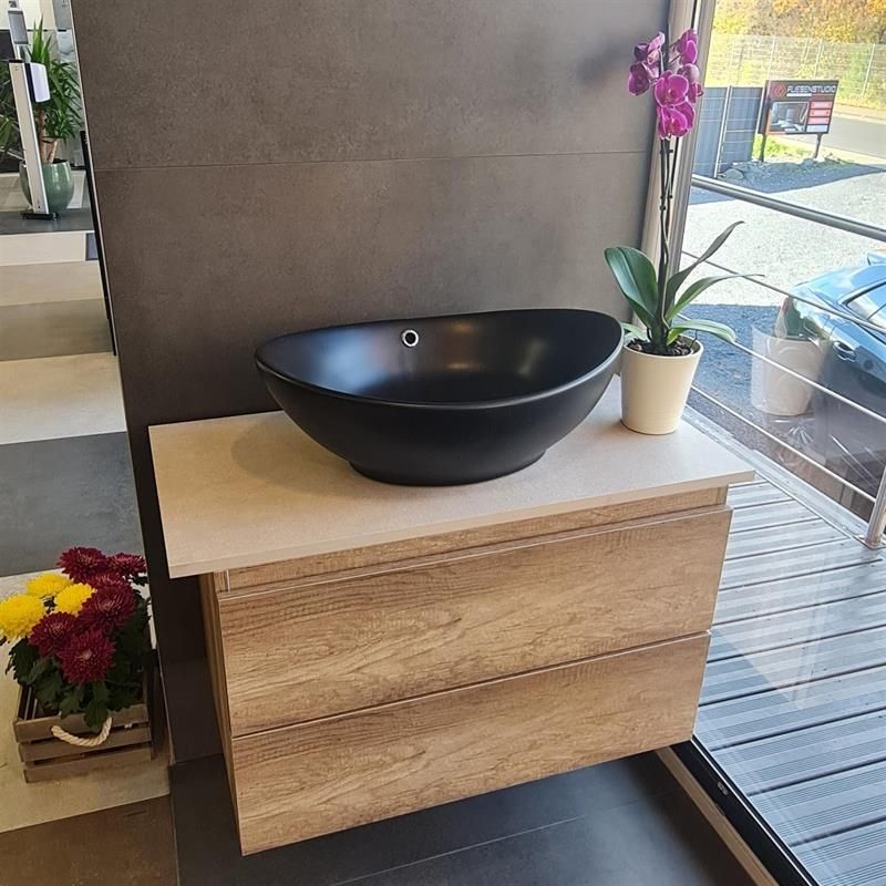 Auf einem Holzschrank steht ein schwarzes Waschbecken.