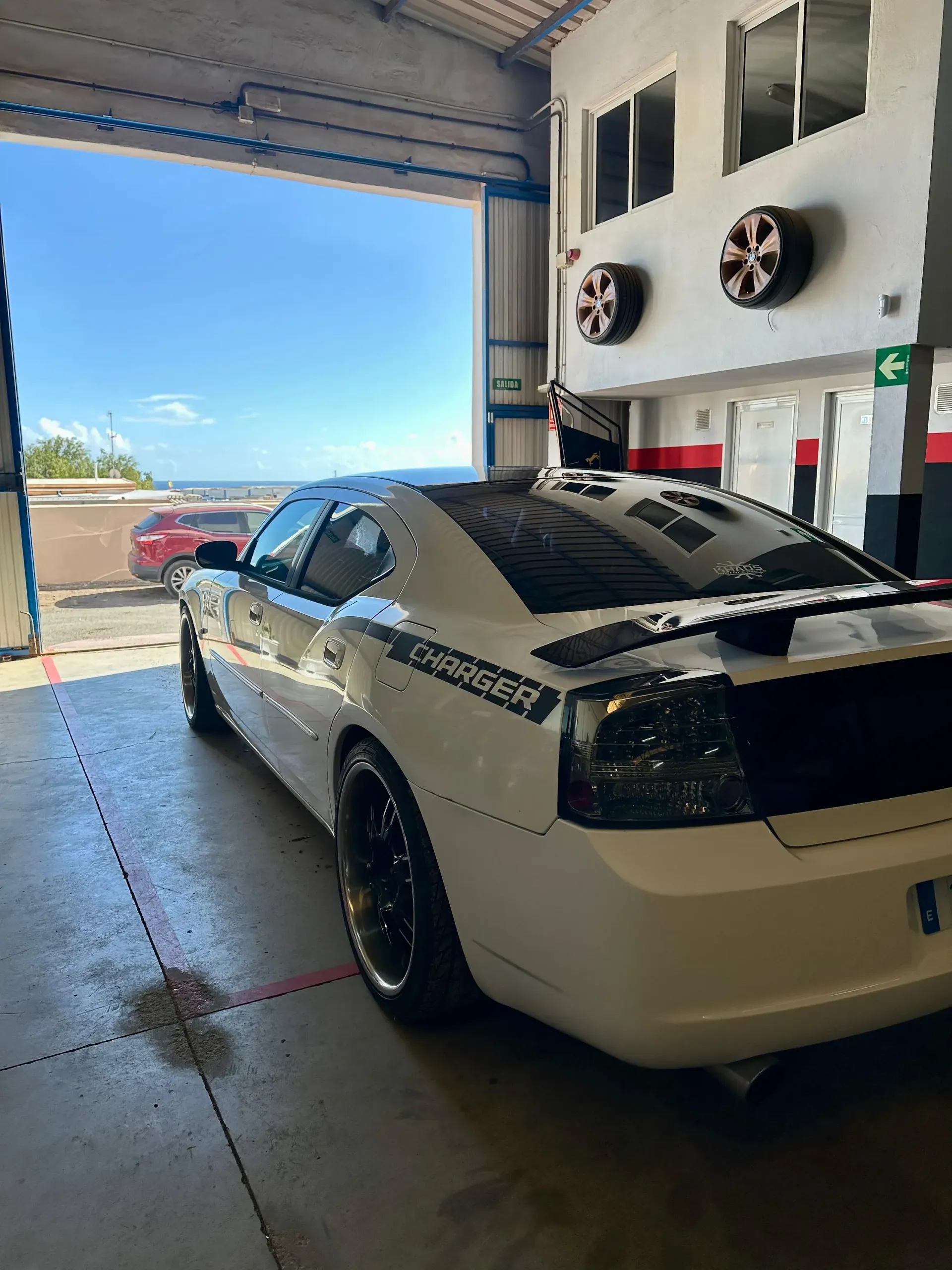 Un Dodge Charger blanco está estacionado en un garaje.