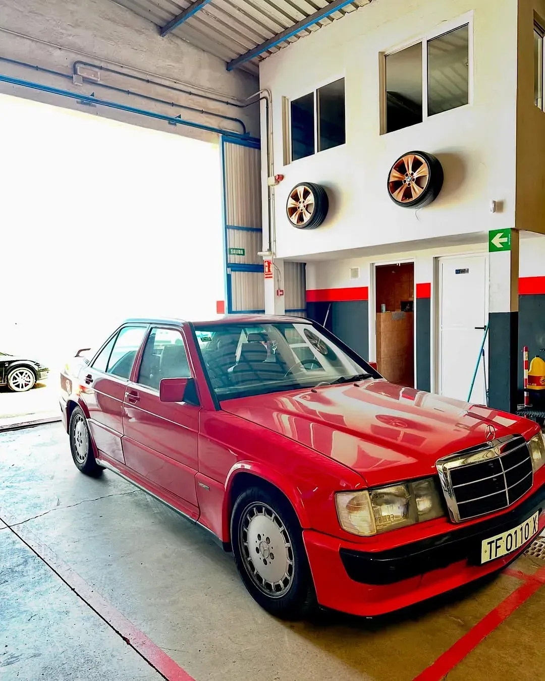 Un Mercedes Benz rojo está aparcado en un garaje.