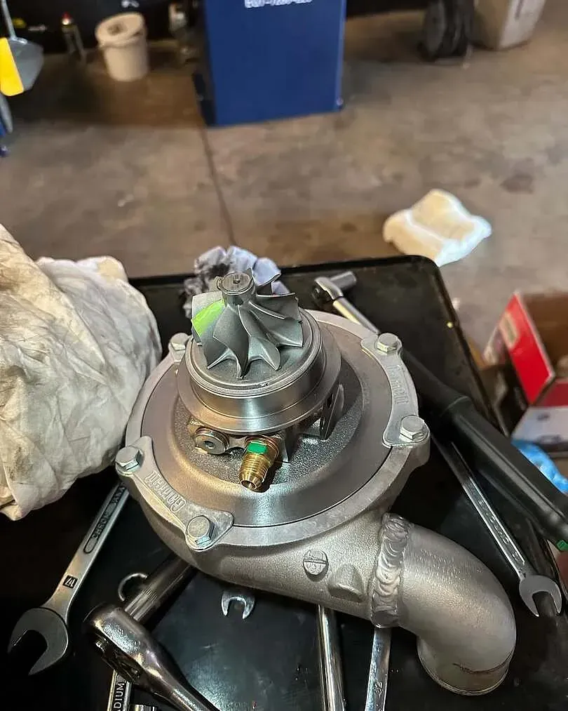 Un turbocompresor está sentado encima de una mesa con herramientas.