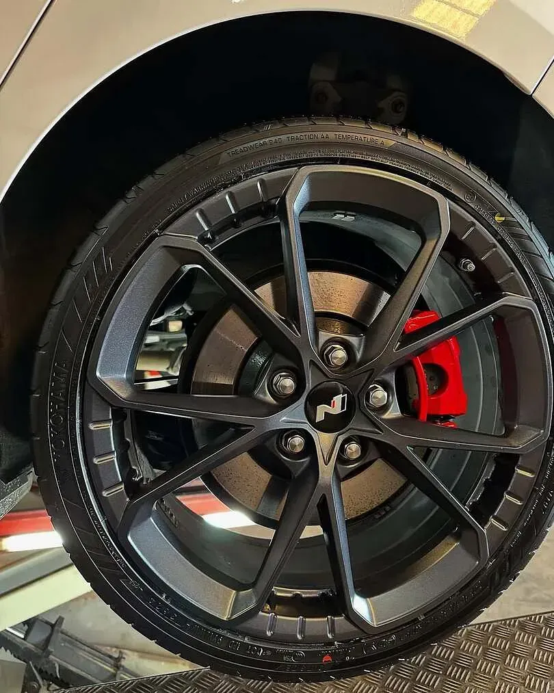 Un primer plano de una rueda de automóvil con una pinza de freno roja.