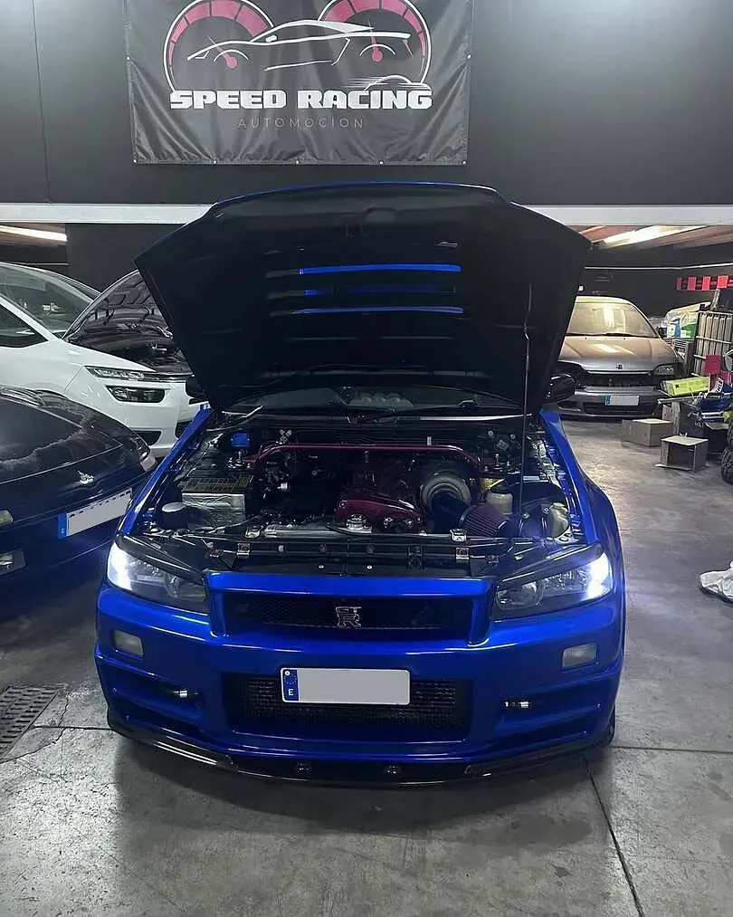 Un coche azul con el capó levantado está aparcado en un garaje.