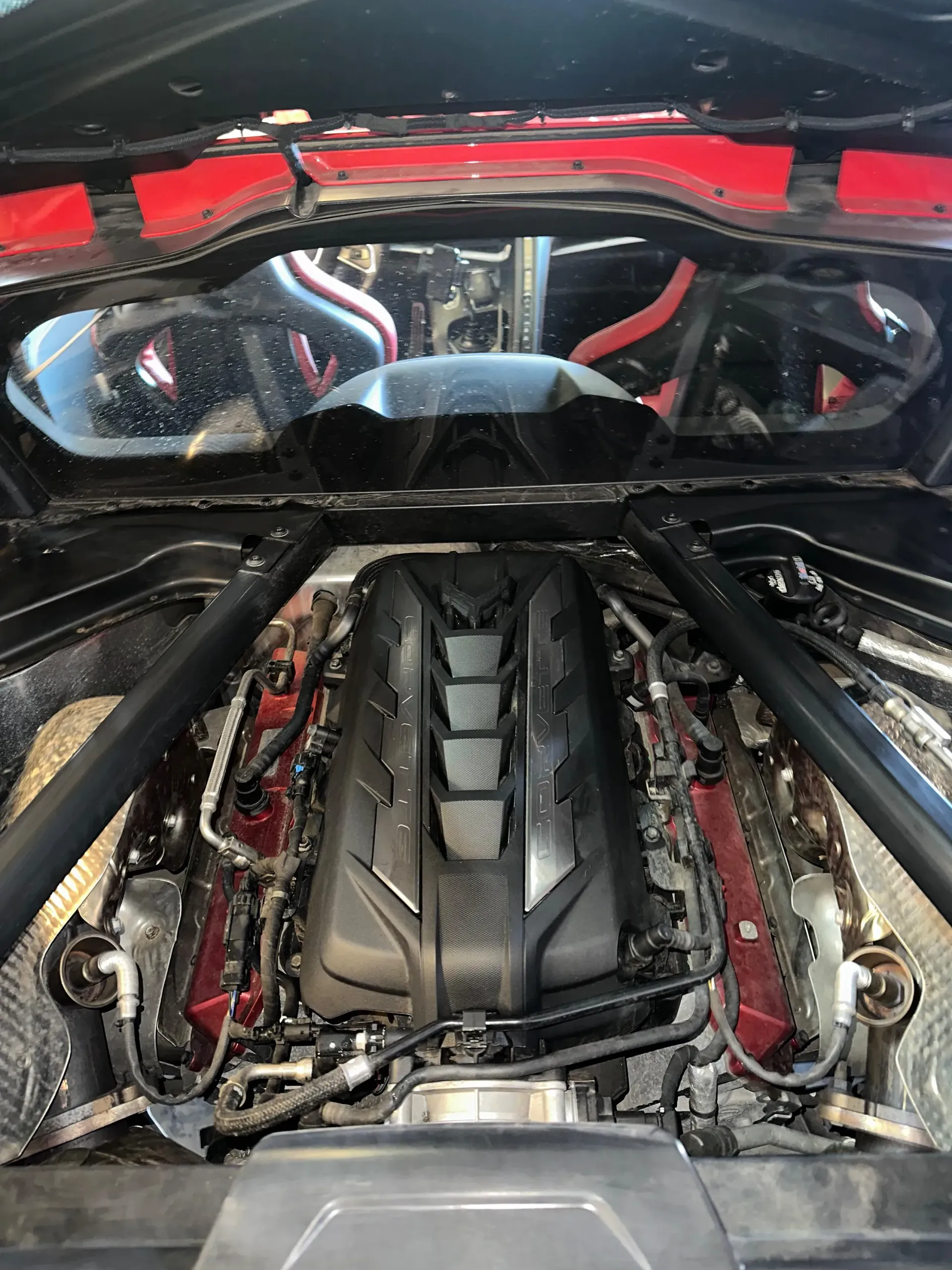 Un primer plano del motor de un coche deportivo con el capó abierto.