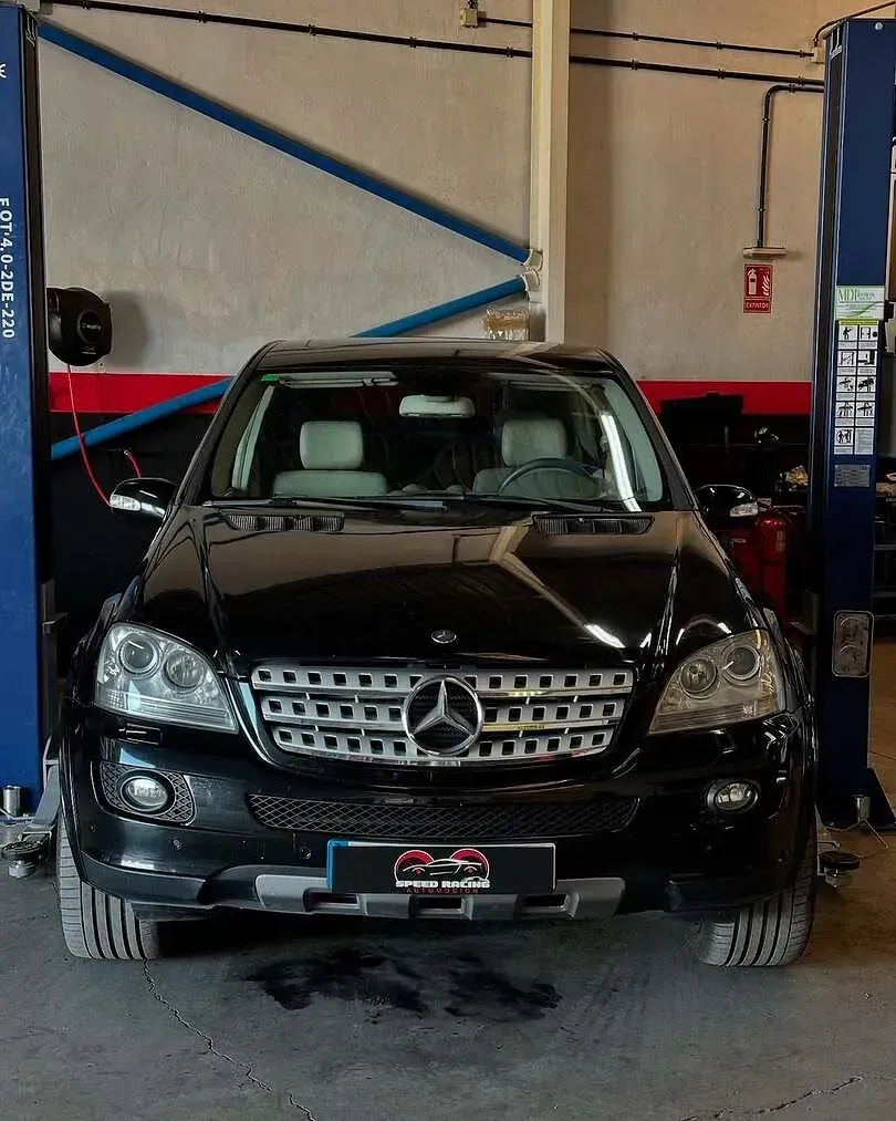 Un Mercedes negro está en un elevador en un garaje.