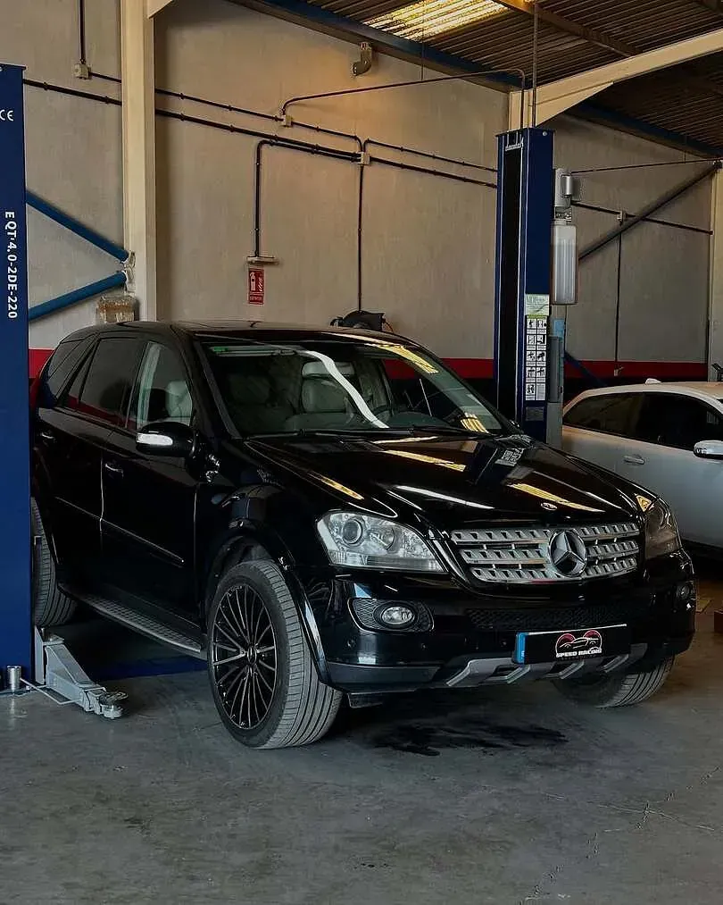 Un todoterreno negro está estacionado en un elevador en un garaje.