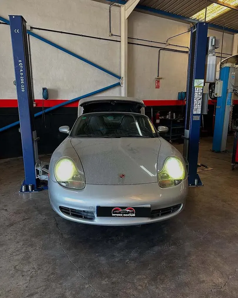 Un Porsche plateado está parado en un elevador en un garaje.