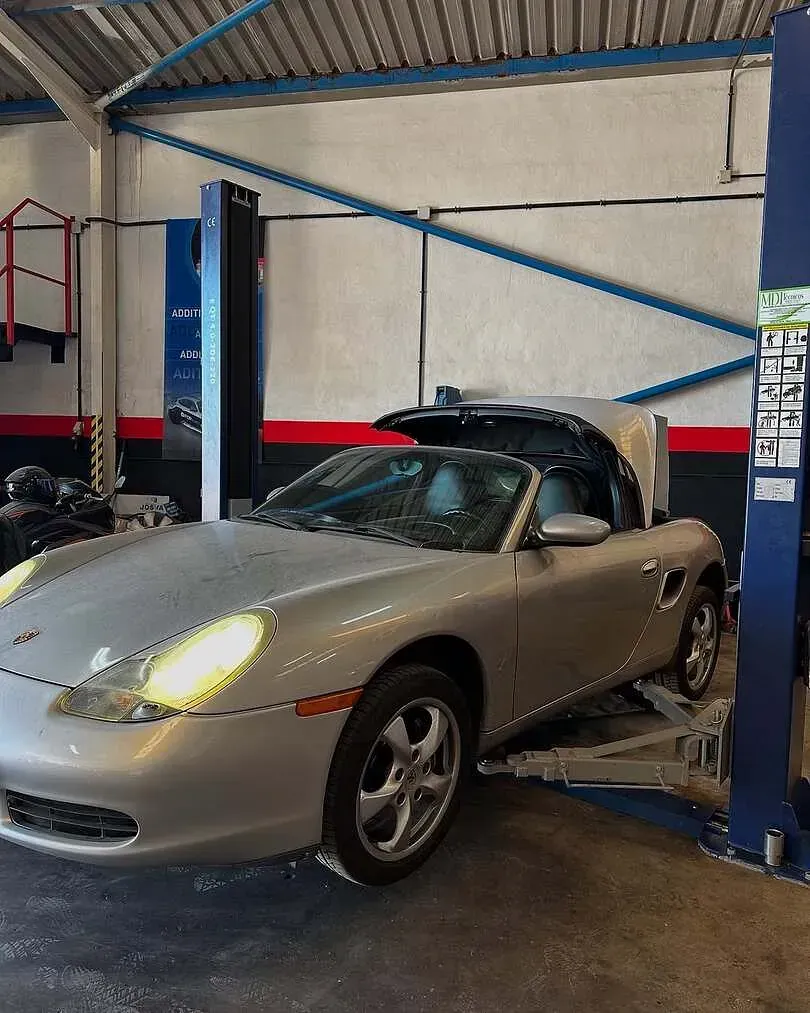 Un coche deportivo plateado está estacionado en un elevador en un garaje.