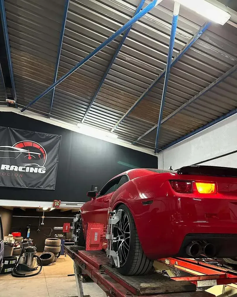 Un coche rojo está estacionado encima de una rampa en un garaje.