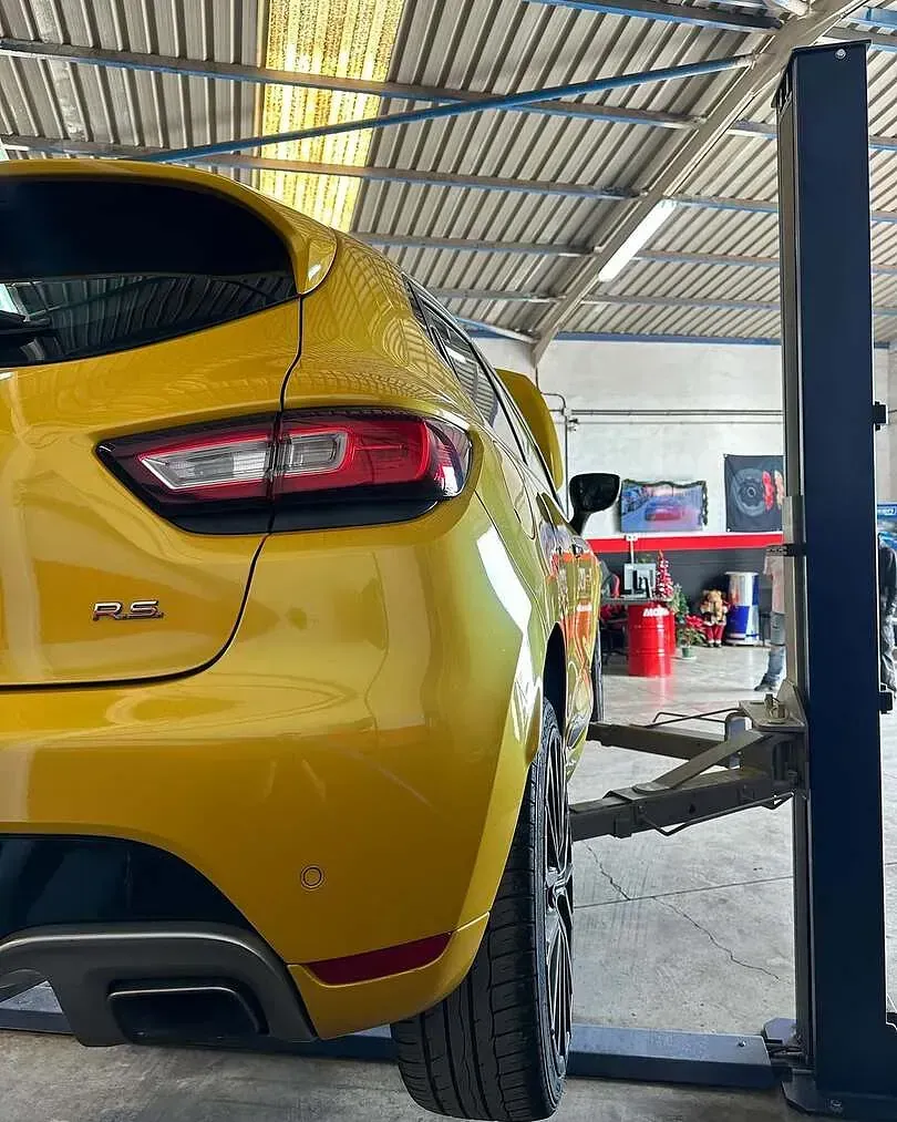 Un coche amarillo está estacionado en un elevador en un garaje.