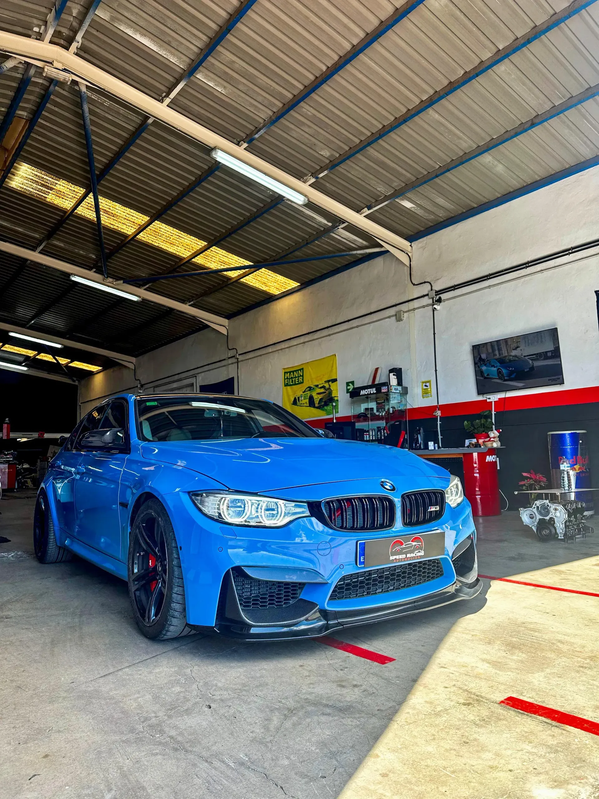 Un BMW M4 azul está aparcado en un garaje.