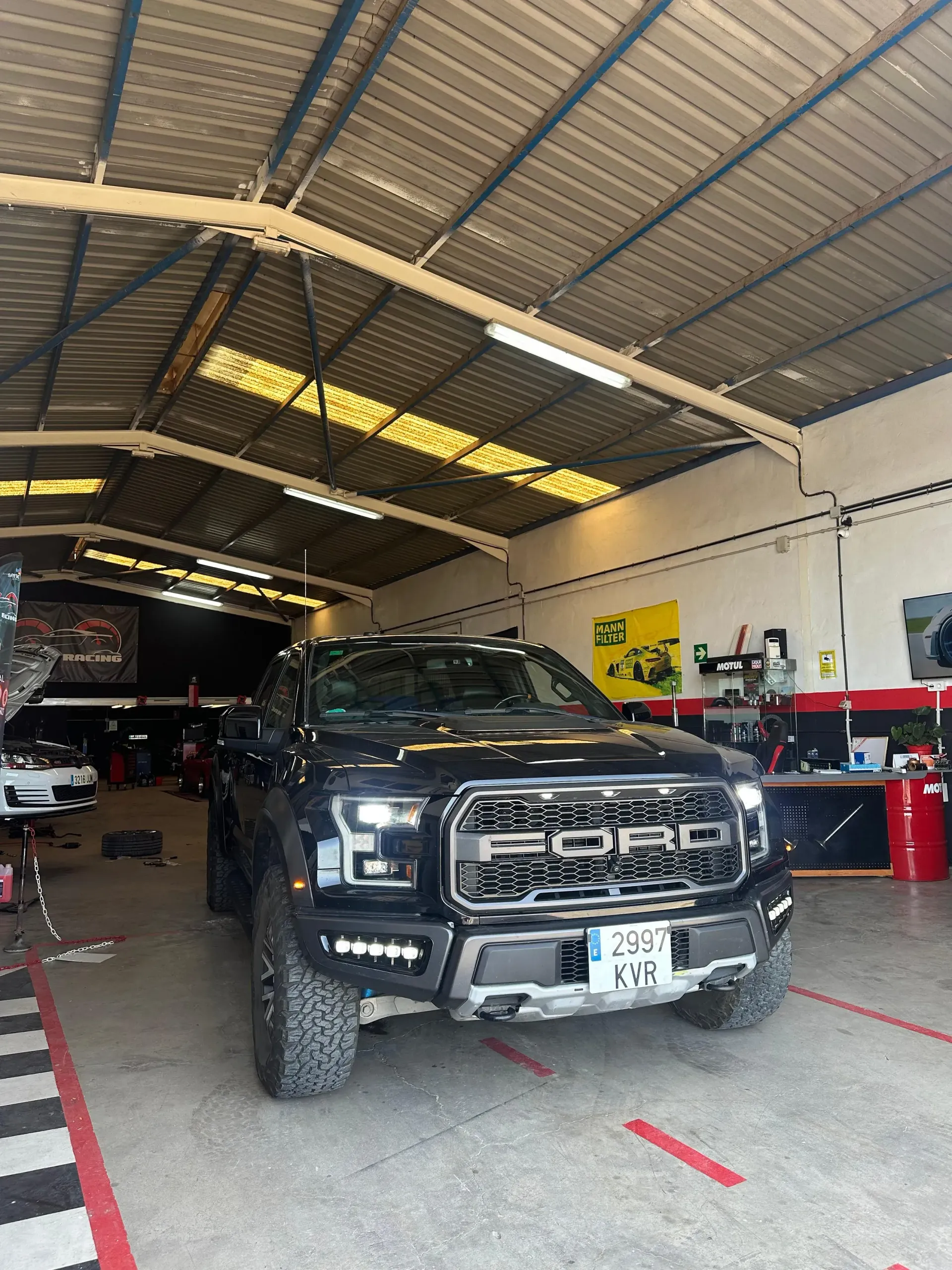 Un Ford Raptor negro está estacionado en un garaje.